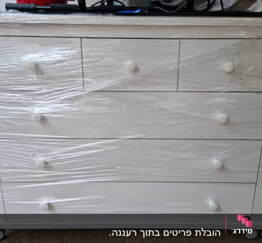 שידה לבנה עטופה בניילון נצמד עם גלגלים